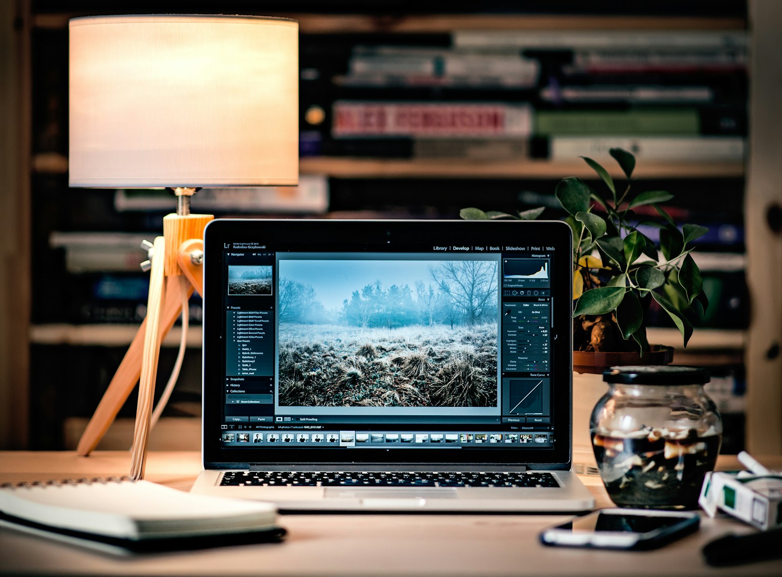 Mesa de trabalho com laptop, abajur de luz quente e estante de livros — ambiente de estratégia e análise Sábia